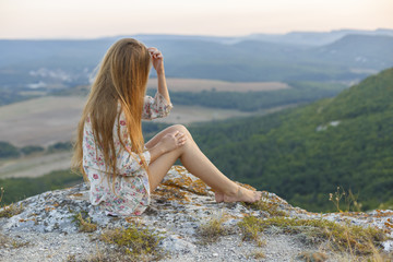 a girl on the edge of a cliff in the mountains