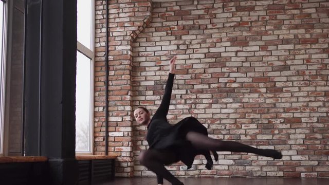 Ballerina is dancing in a training hall.She is whirling and falling on a floor then rising