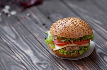 Closeup of home made beef burgers with lettuce and mayonnaise served on little wooden board. Dark background