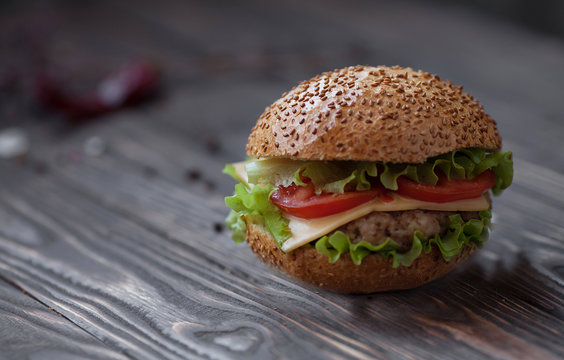 Closeup of home made beef burgers with lettuce and mayonnaise served on little wooden board. Dark background