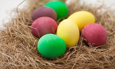 Fototapeta na wymiar Easter eggs in the nest on white wooden background