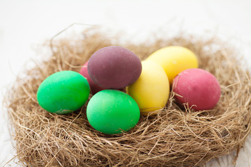 Fototapeta premium Easter eggs in the nest on white wooden background