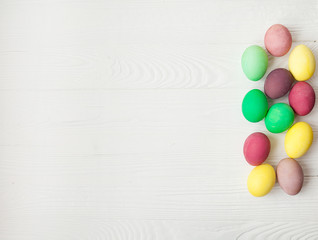 Colorful Easter eggs on white wooden background.