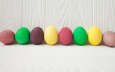 Colorful Easter eggs on white wooden background.
