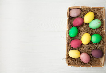 Easter eggs in the nest on white wooden background