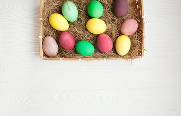 Easter eggs in the nest on white wooden background