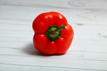 On the white wooden table you can see the top of red bell pepper.