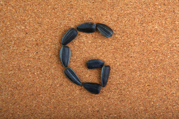 Black Sunflower Seeds Alphabet wooden background 