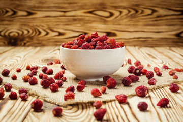 red strawberries in bowl on a wooden background