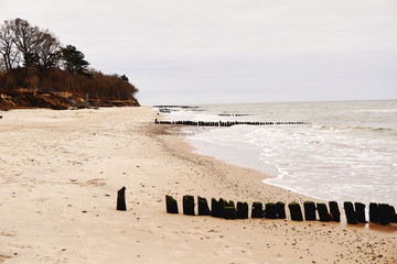 Picturesque sea shore with breakwaters in autumn scenery.