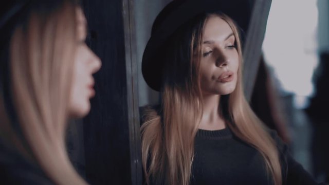 A stylish girl in a black hat makes selfie iron her hair
