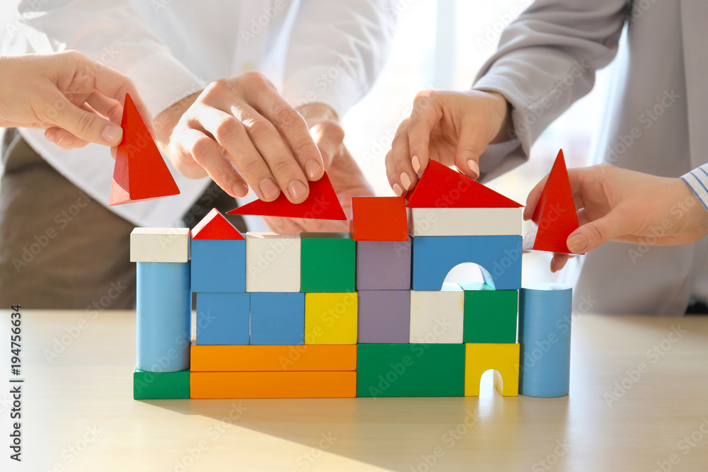 Wall mural People building house together on table, closeup. Unity concept