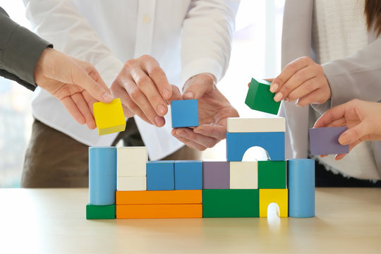 People building house together on table, closeup. Unity concept