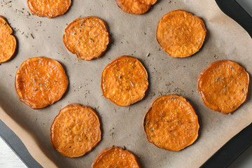 Tasty sweet potato chips on baking tray, top view