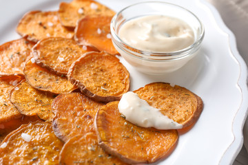 Tasty sweet potato chips and sauce on plate, closeup