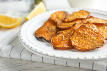 Plate with tasty sweet potato chips on table, closeup