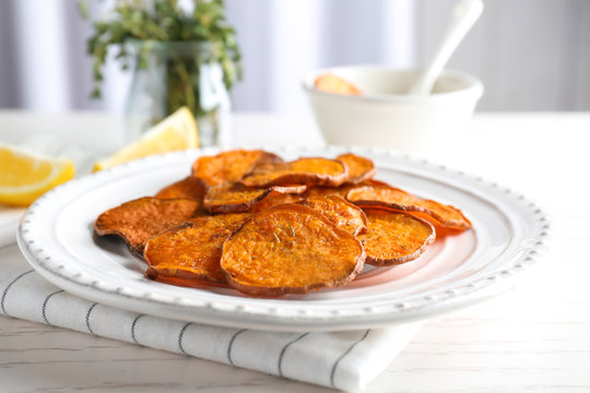 Plate with tasty sweet potato chips on table, closeup