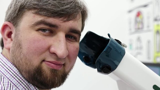 Patient in ophthalmology clinic. Man looks at the camera near apparatus for the treatment of spasm of accommodation, amblyopia and binocular vision disorders