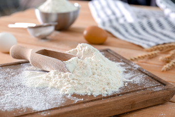 Wheat flour and scoop on wooden board