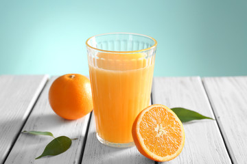Glass with fresh orange juice and fruit on wooden table