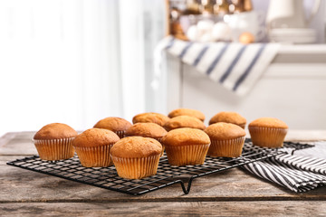 Cooling rack with tasty cupcakes on table. Fresh from oven