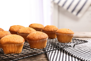 Cooling rack with tasty cupcakes on table. Fresh from oven