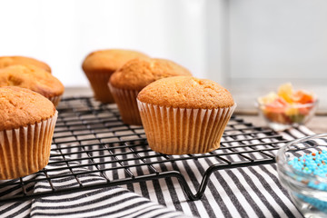 Cooling rack with tasty cupcakes on table. Fresh from oven
