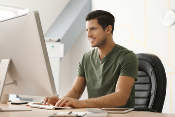 Fototapeta premium Young man working with computer in office