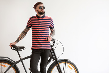 Fototapeta na wymiar Portrait of handsome hipster with bicycle on light background