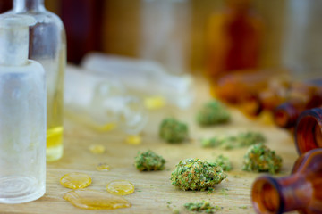 Medical Oil of Cannabis -  view of marijuana oil, leaking resin from old antique apothecary jar and marijuana flowers on fresh oak wood background.