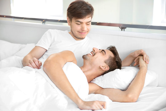 Young gay couple lying in bed at home