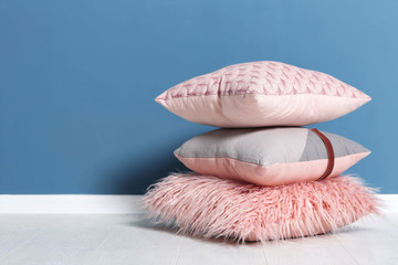 Stack of soft pillows on floor near color wall