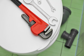 Plumber's tools on toilet seat lid indoors