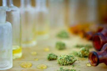 Medical Oil of Cannabis -  view of marijuana oil, leaking resin from old antique apothecary jar and marijuana flowers on fresh oak wood background.