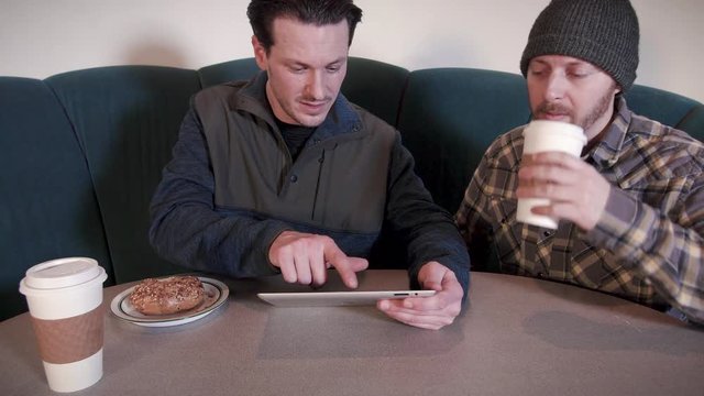 Two Young Businessmen Working on Tablet Computer Brainstorming in Cafe