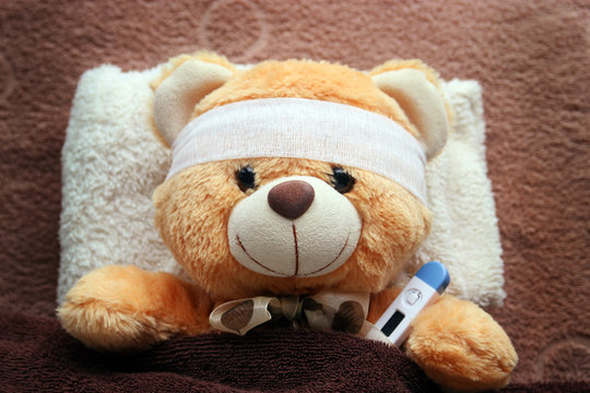 Teddy Bear with thermometer lying in the . Teddy bear ill