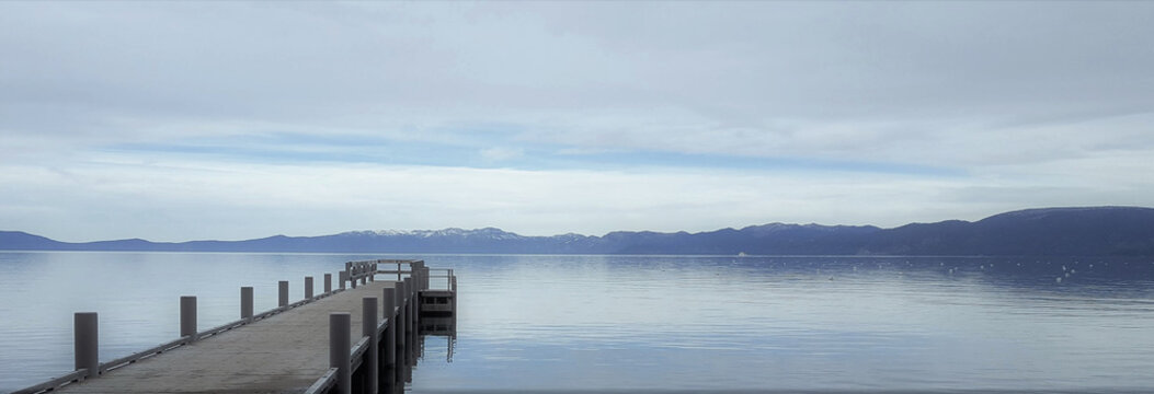 Fototapeta Moody pier reaching out into a serene lake.
