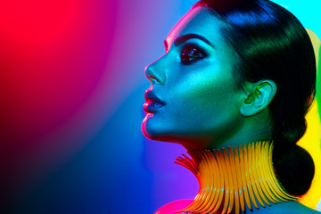 Fashion model woman in colorful bright lights posing. Portrait of beautiful sexy girl with trendy makeup