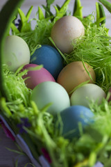 Colorful easter eggs in the decorative basket on a white wooden background