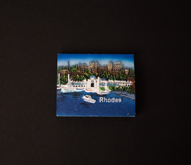 Souvenir - Fridge magnet from Rhodes, Greece on black background