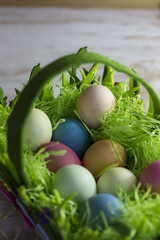 Fototapeta na wymiar Colorful easter eggs in the decorative basket on a white wooden background