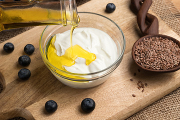 Flax seed oil is being poured over cottage cheese in a bowl