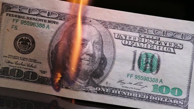 Dollar bill in flames. American money burning on black background. Economic crisis or inflation concept. For this video it is used fake bank notes.