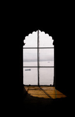 Shadowy view on Ganga river through the islamic pattern window. Smoky sunrise and boats on backside. Varanasi  (Banaras). India.
