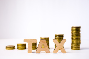 Tax concept photo. Tax word from 3D volumetric letters is in foreground to background of blurred columns or stacks of coins in exit order. Visualization of tax charging and payment in business