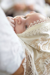Father (caucasian young man) holding little infant kid in baptism (christening) ceremony in church