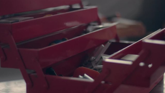 worker in his garage with a red tool storage box preparing for work