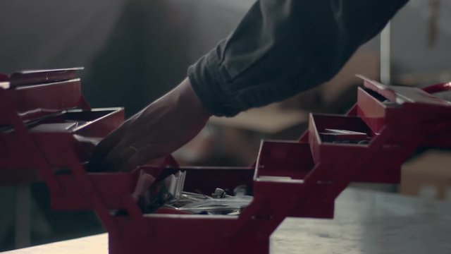 worker in his garage with a red tool storage box preparing for work