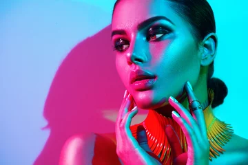 Foto op Plexiglas Mannequin vrouw in kleurrijke felle lichten met trendy make-up en manicure poseren in studio © Subbotina Anna