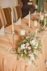 Wedding table decor full of rose and eustoma flowers, candles and peach colored fabric. Luxury rich restaurant interior. Indoor. Copy space